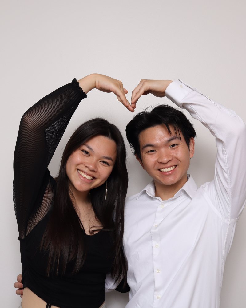 A couple making a heart shape with their arms in the Stella Booth